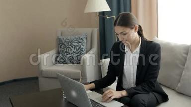年轻女子在<strong>现代办公桌</strong>上工作，手提电脑，忙于远程学习，在酒店房间。 女老板